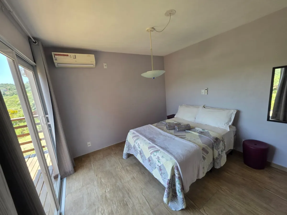 Lar do Sol: quarto com cama de casal, ar-condicionado e porta de vidro para a varanda com vista para os morros
